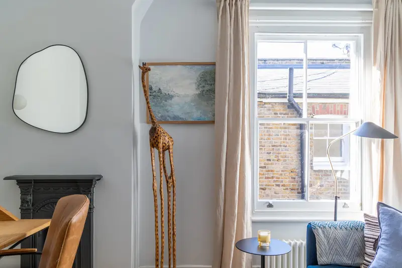 Balham living room corner with a sculptural mirror and blue armchair