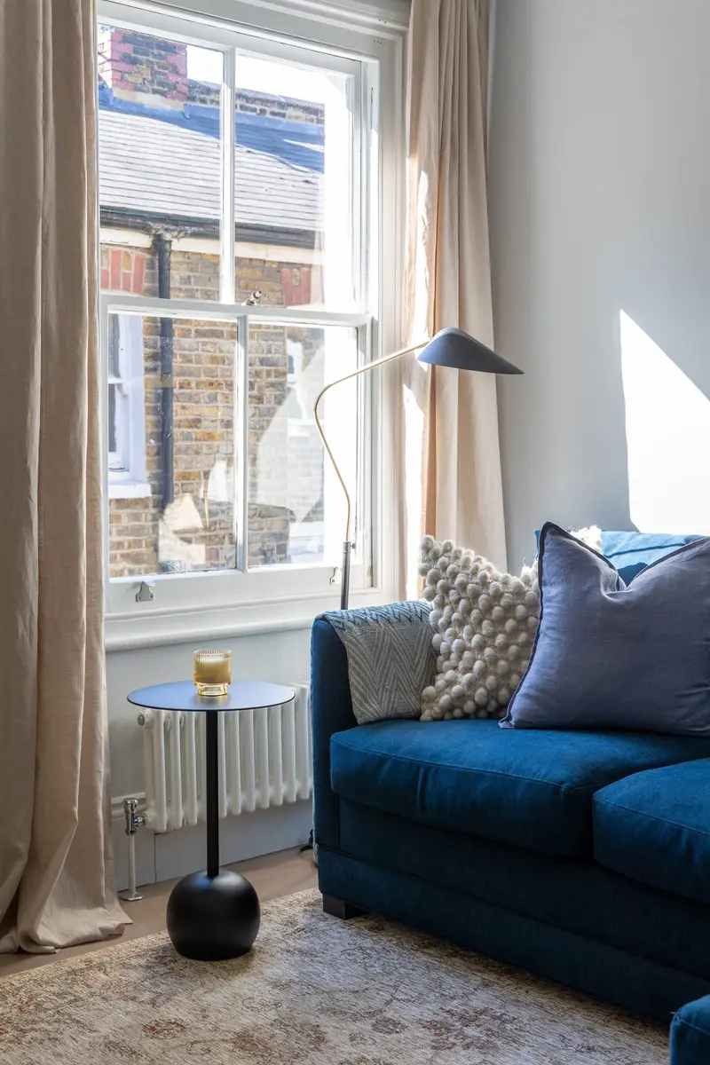 Window corner with a navy sofa and floor lamp