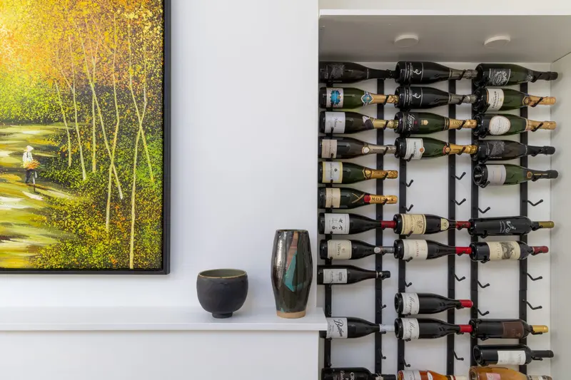 Built-in wine storage wall beside a forest painting