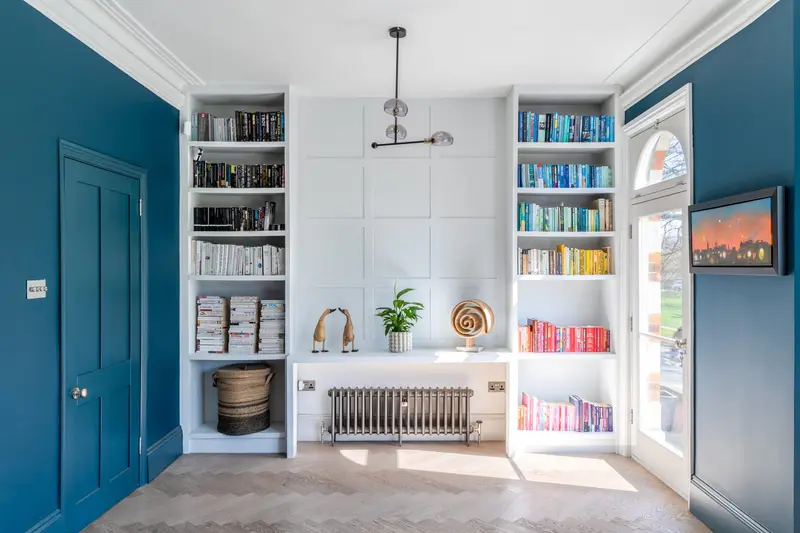 Teal living room with white bookshelves and a garden door