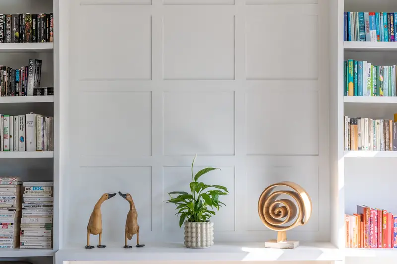 Panelled wall with colourful bookshelves either side