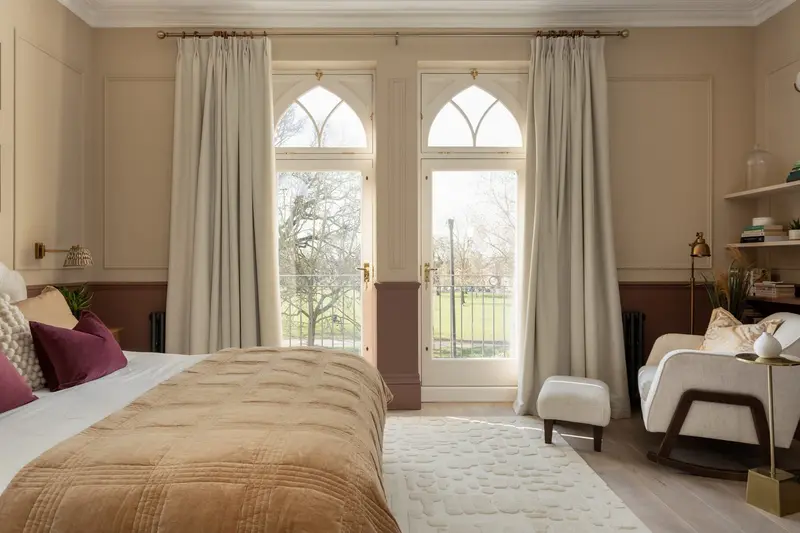 Balham bedroom with arched French windows, plum bedding and a velvet ottoman