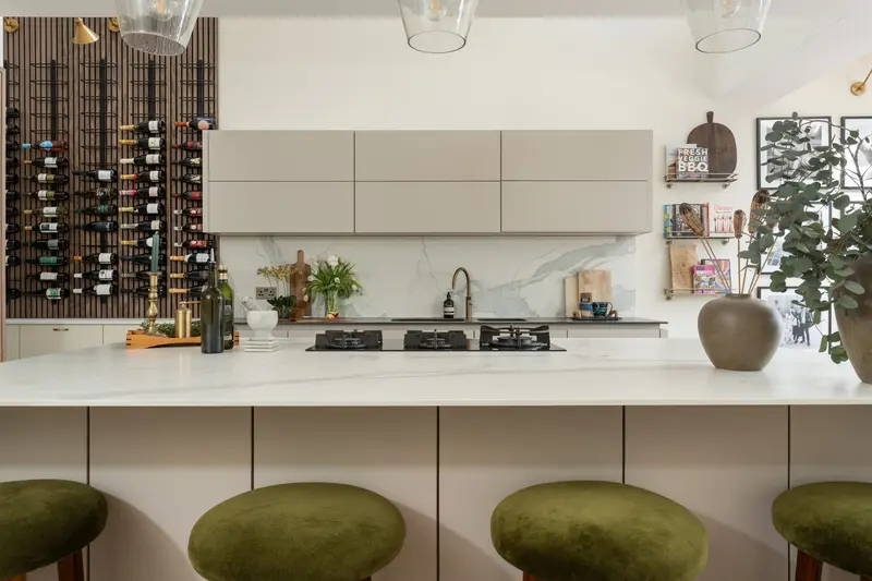 Kitchen island with olive velvet bar stools and a full-height wine wall