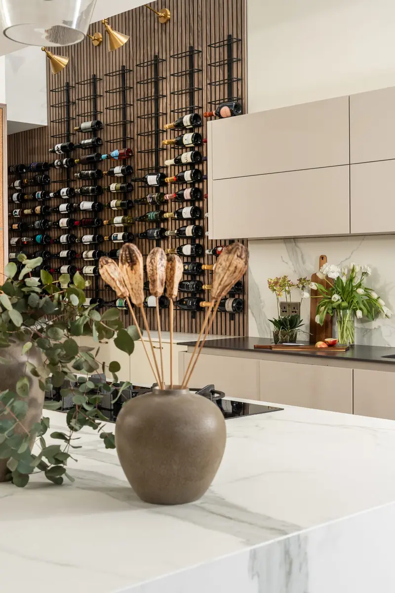 Kitchen with a marble island, ceramic vase and black metal wine racking