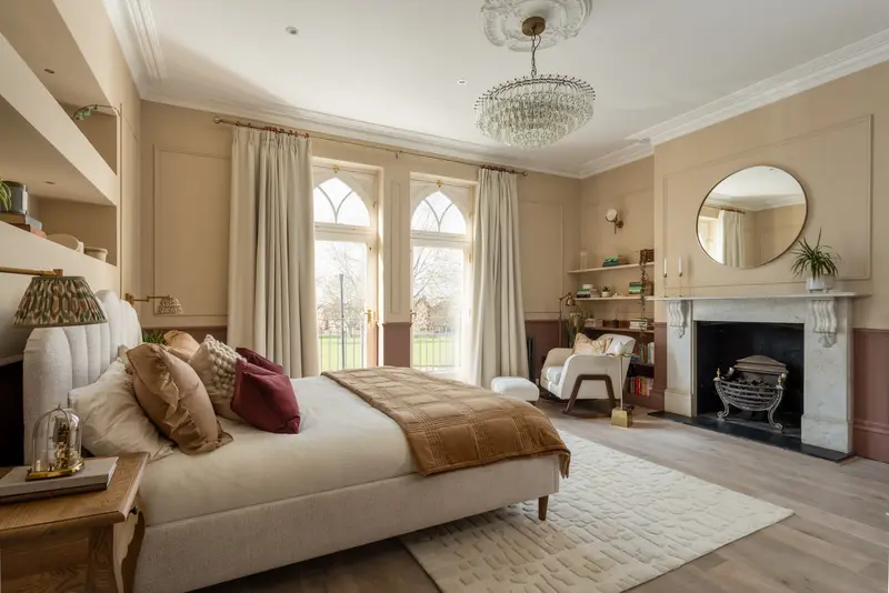 Main bedroom with a chandelier, fireplace and arched windows