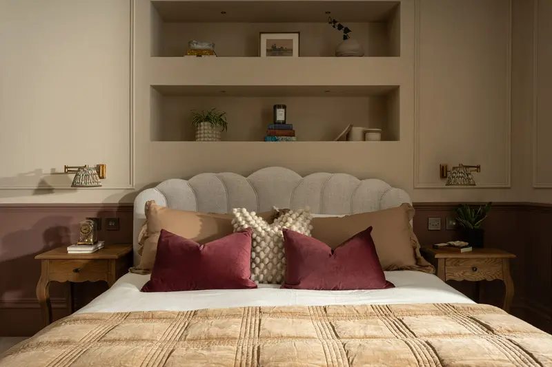 Scalloped headboard with burgundy cushions in a warm neutral bedroom