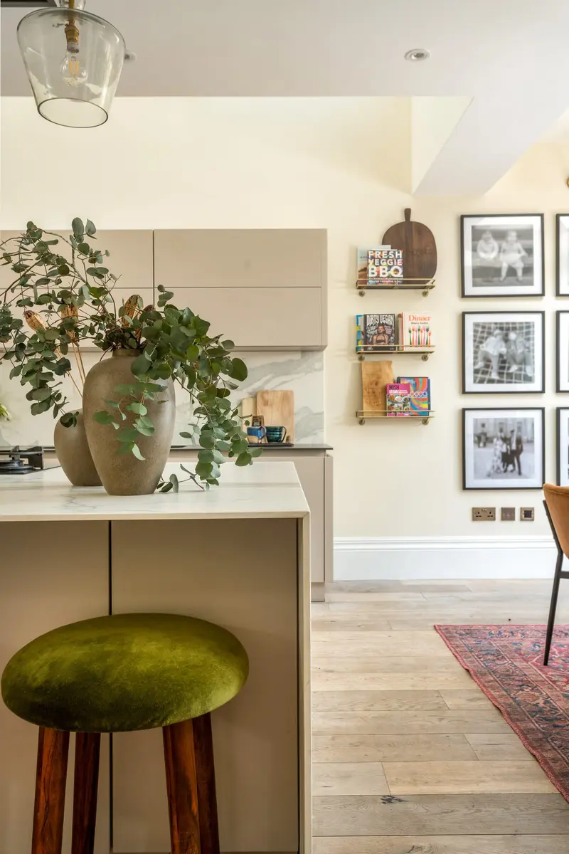 Kitchen corner with an olive velvet stool and gallery wall