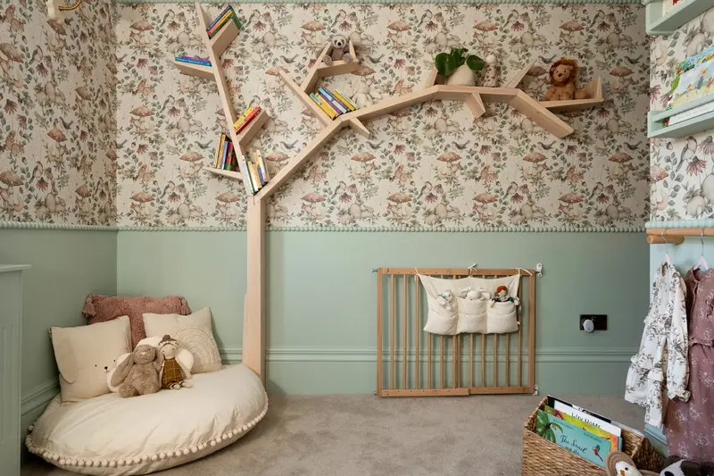 Nursery with a tree bookshelf and floral wallpaper