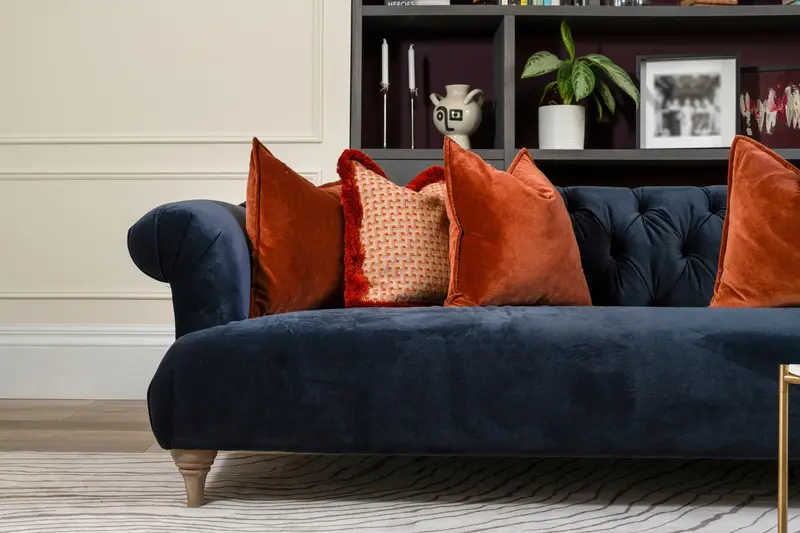 Navy velvet chesterfield with burnt orange cushions