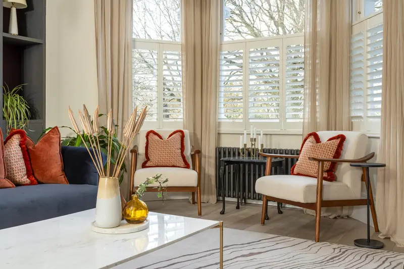 Bay window seating area with rust cushions and a marble coffee table