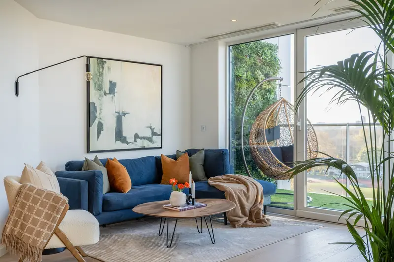 Penthouse living room with a navy sofa, hanging egg chair and park views