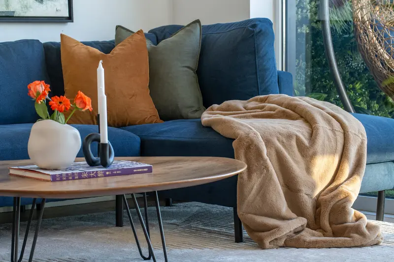 Navy sofa with a caramel throw and oval coffee table