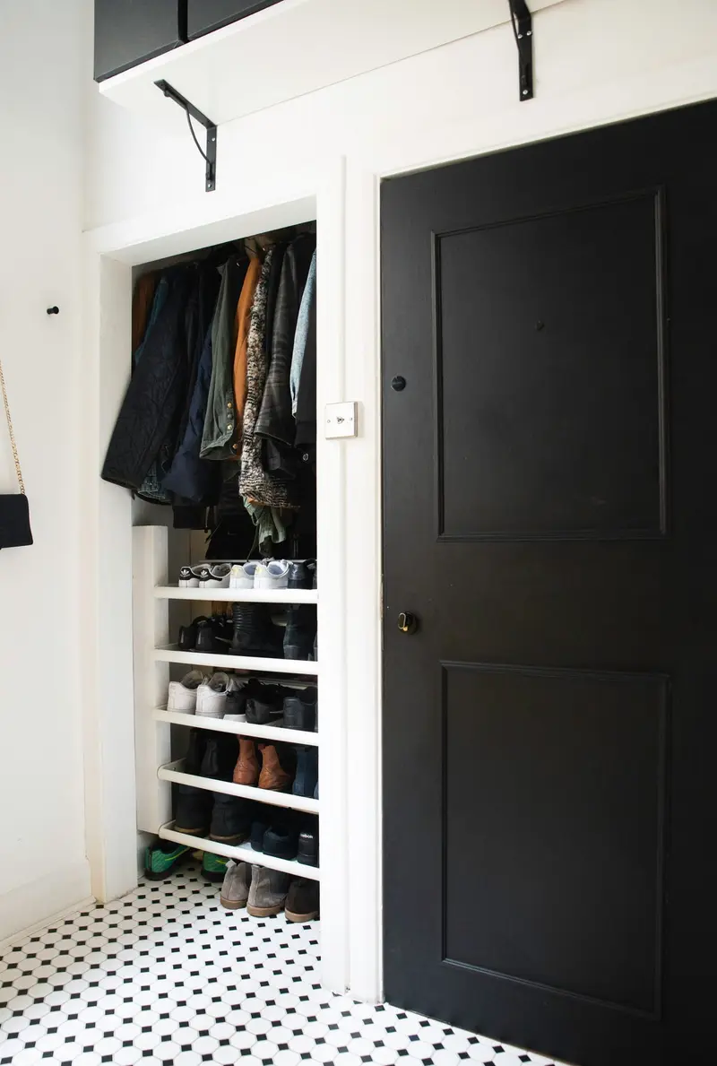 Monochrome hallway with open wardrobe and black door