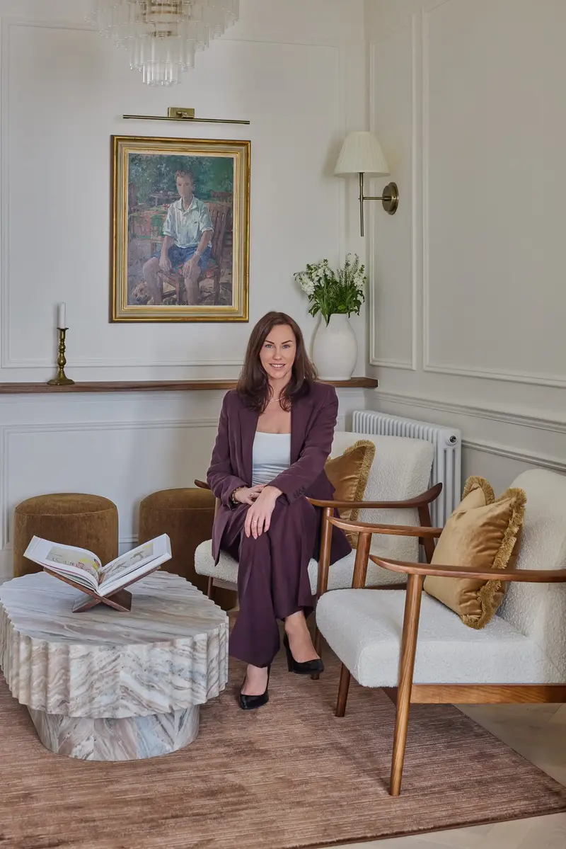 Charlotte Bergman seated in a finished bedroom she designed
