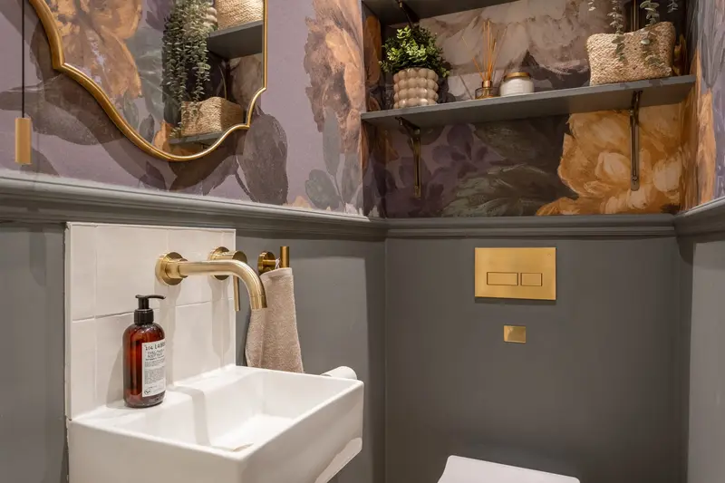 Cloakroom with dramatic floral wallpaper and brass tap