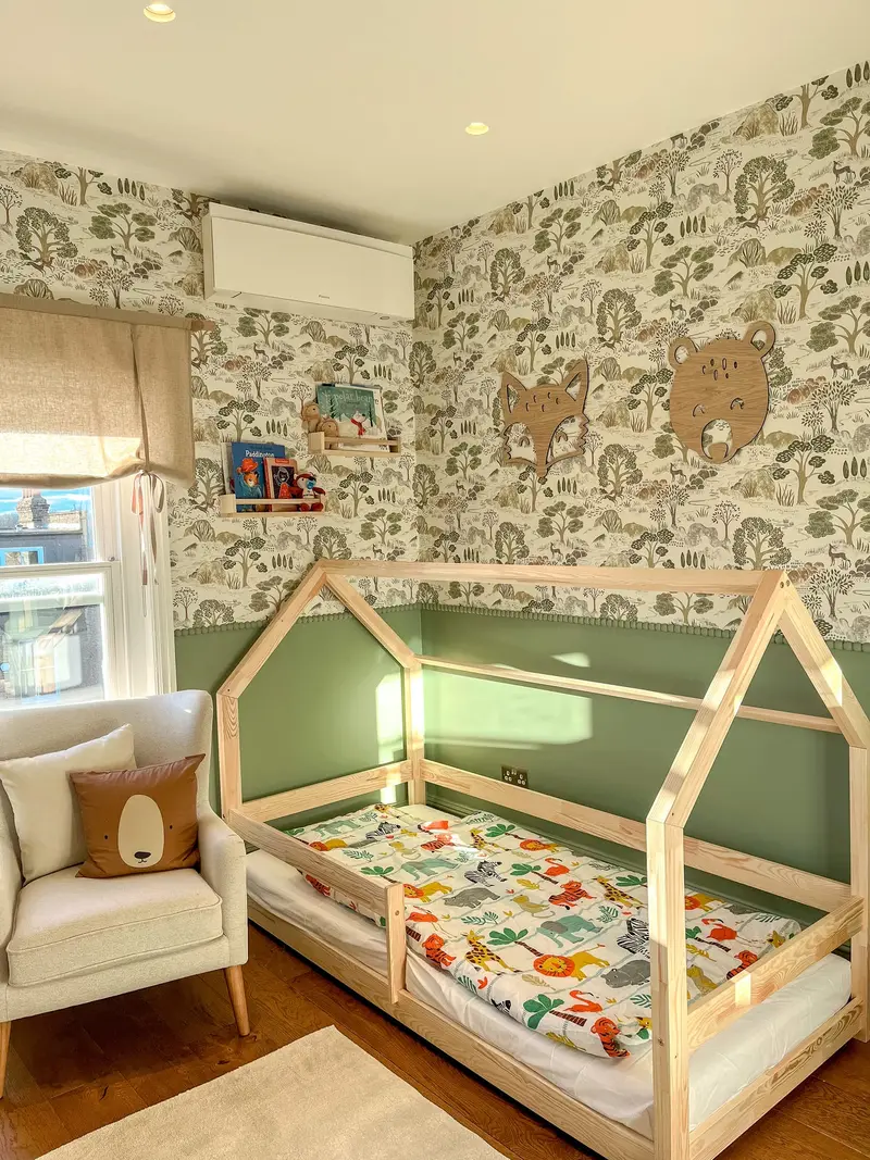 Child’s bedroom with a house-frame bed and woodland wallpaper