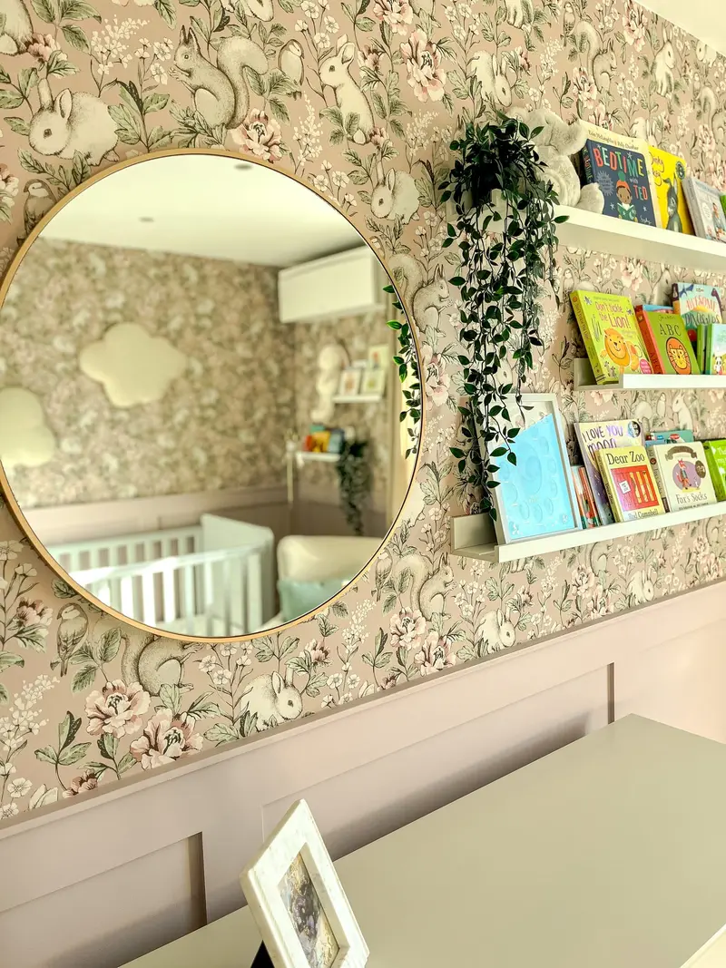 Round mirror and book ledges against woodland wallpaper