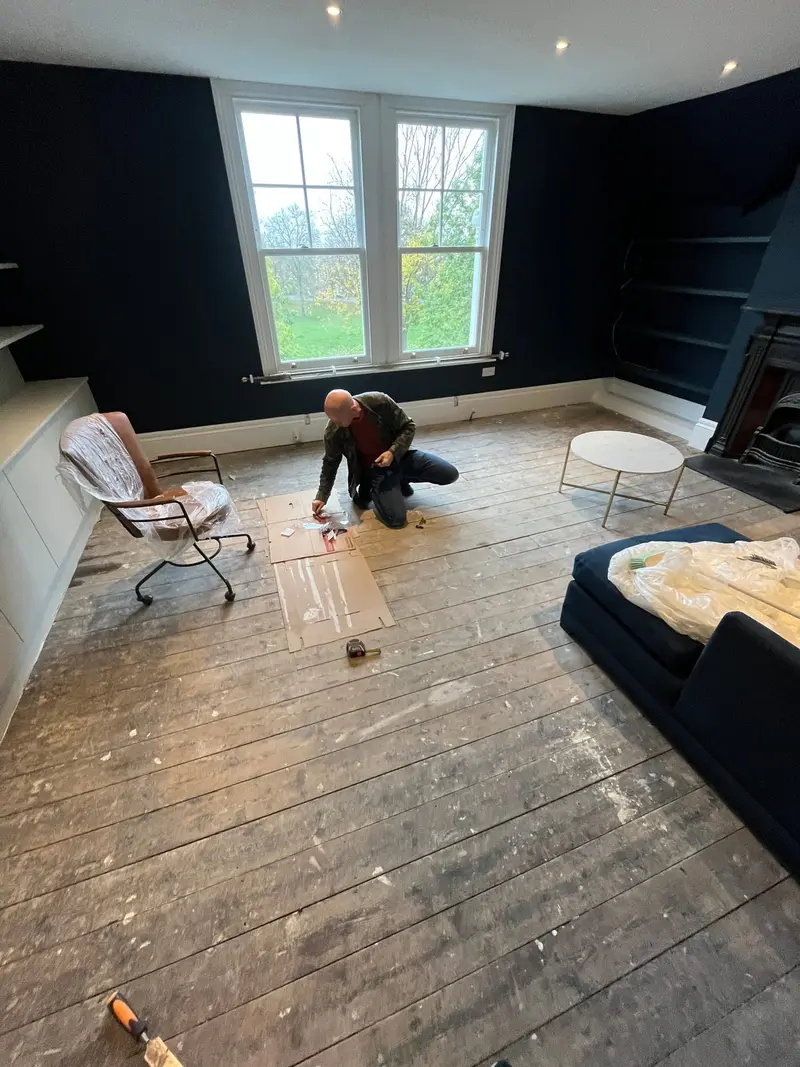 Dark-painted bedroom during works with floorboards exposed
