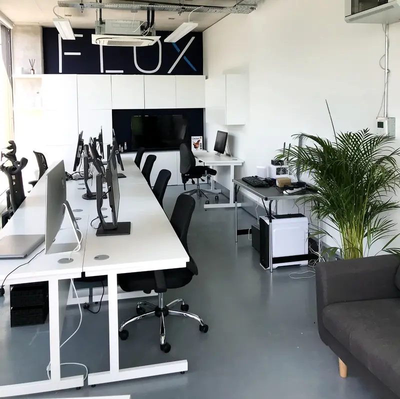 Flox.ai office with paired white desks and a branded storage wall