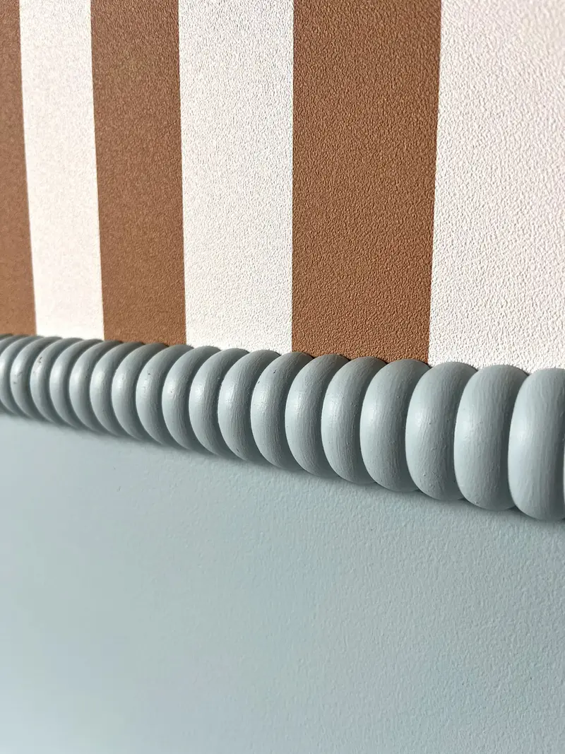Painted stripes and scalloped detail on a child’s bedroom wall