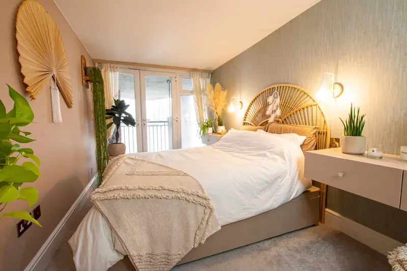 Soft beige bedroom with a rattan headboard and palm-leaf wall fan