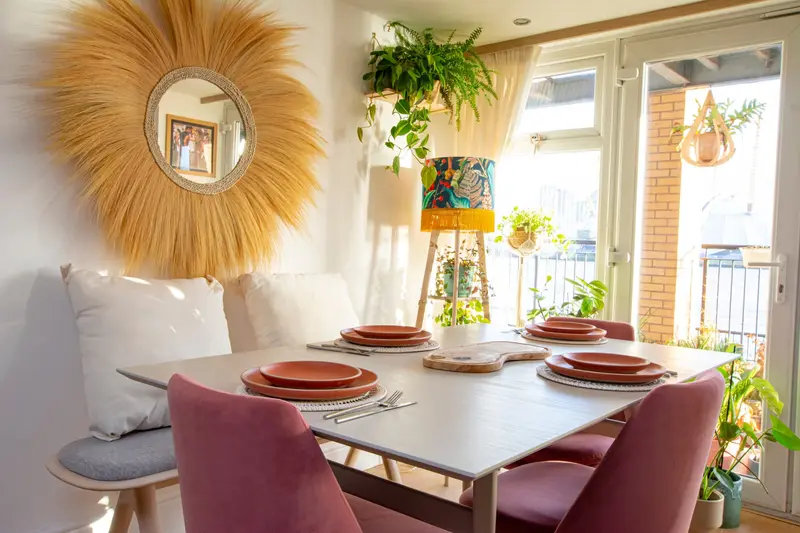 Dining area with a sunburst mirror and plum chairs