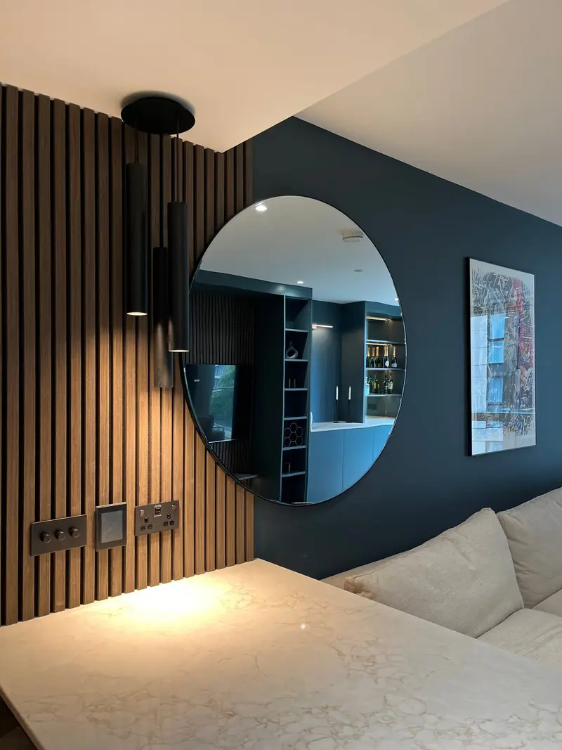 Dark wood panelling, round mirror and moody blue walls in the Paddington flat