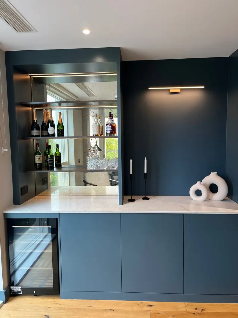Bespoke mirrored bar with a marble worktop and navy cabinets