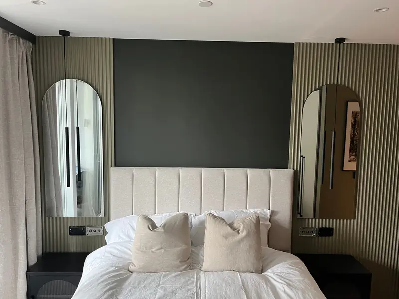 Moody bedroom with a channel-tufted headboard and arched mirrors