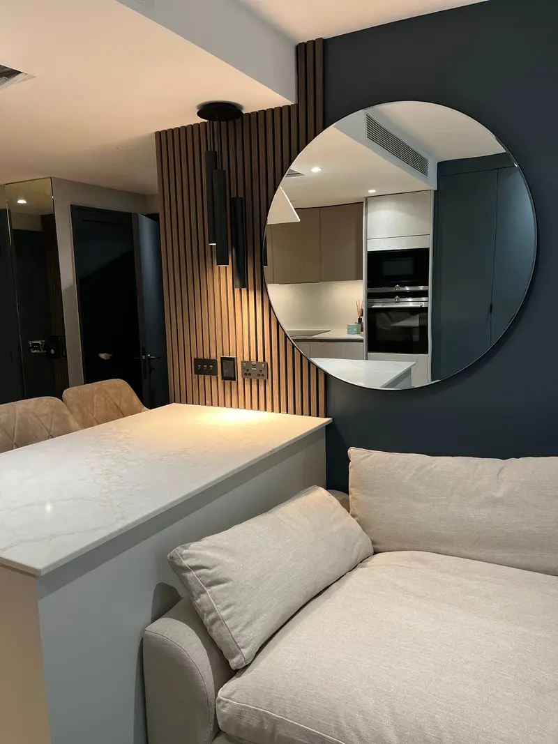 Kitchen view past a round mirror and marble worktop
