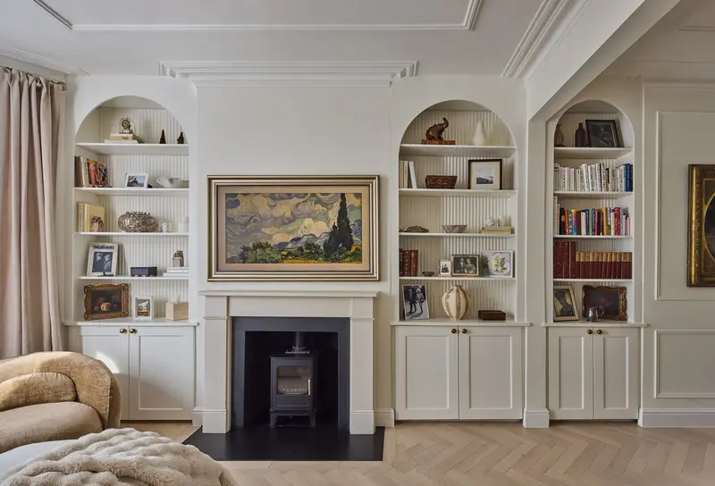 Living room with arched bookshelves, stove and a large framed landscape painting
