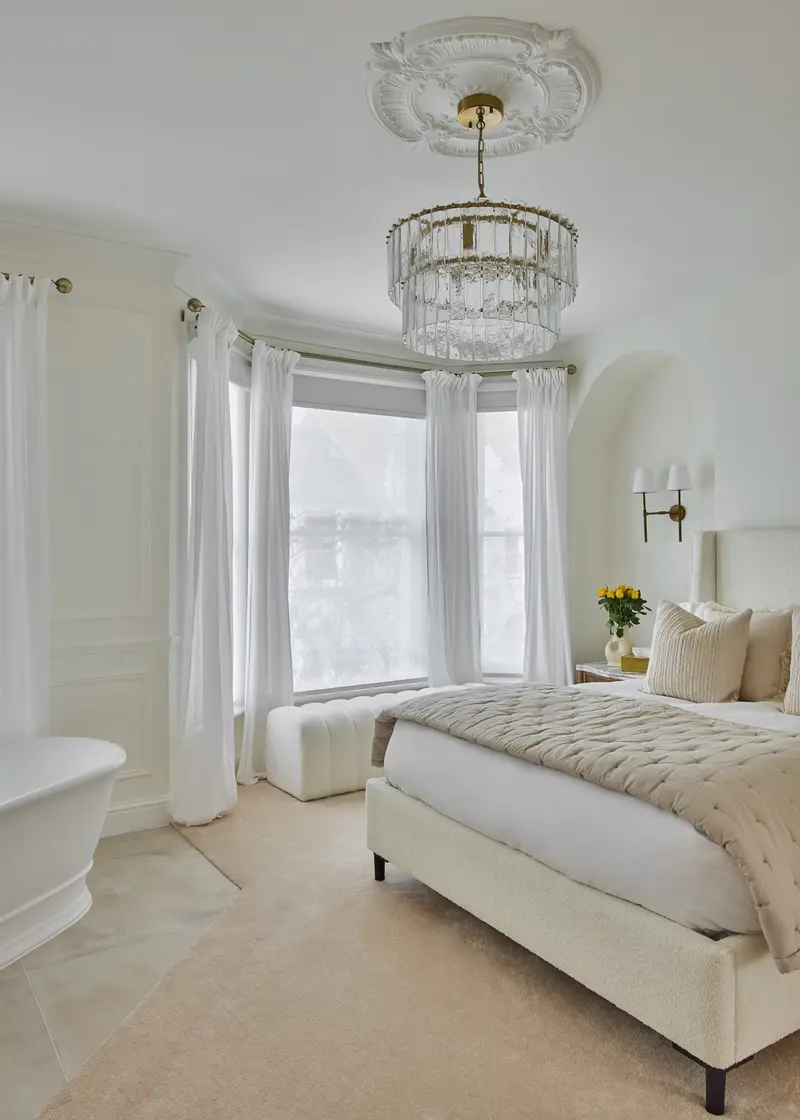 Cream bedroom with a crystal chandelier and floor-length sheer curtains