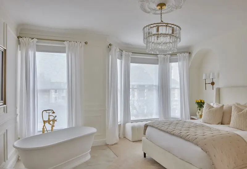Bay-window bedroom with a freestanding bath and crystal chandelier