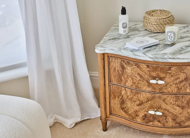 Burr-walnut bedside chest with a marble top and candle styling