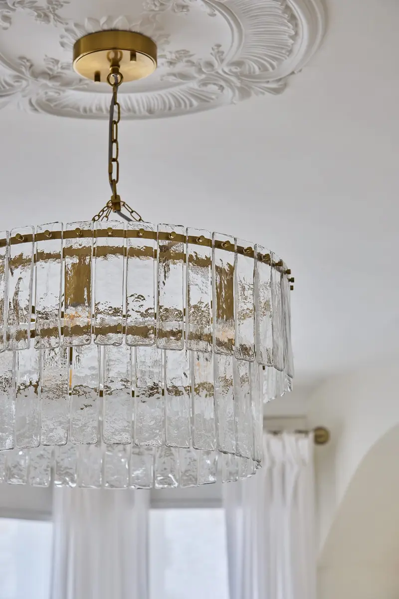 Tiered crystal chandelier hanging from an ornate ceiling rose