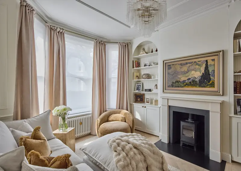 Bay-window living room with a cream sofa, stove and framed painting