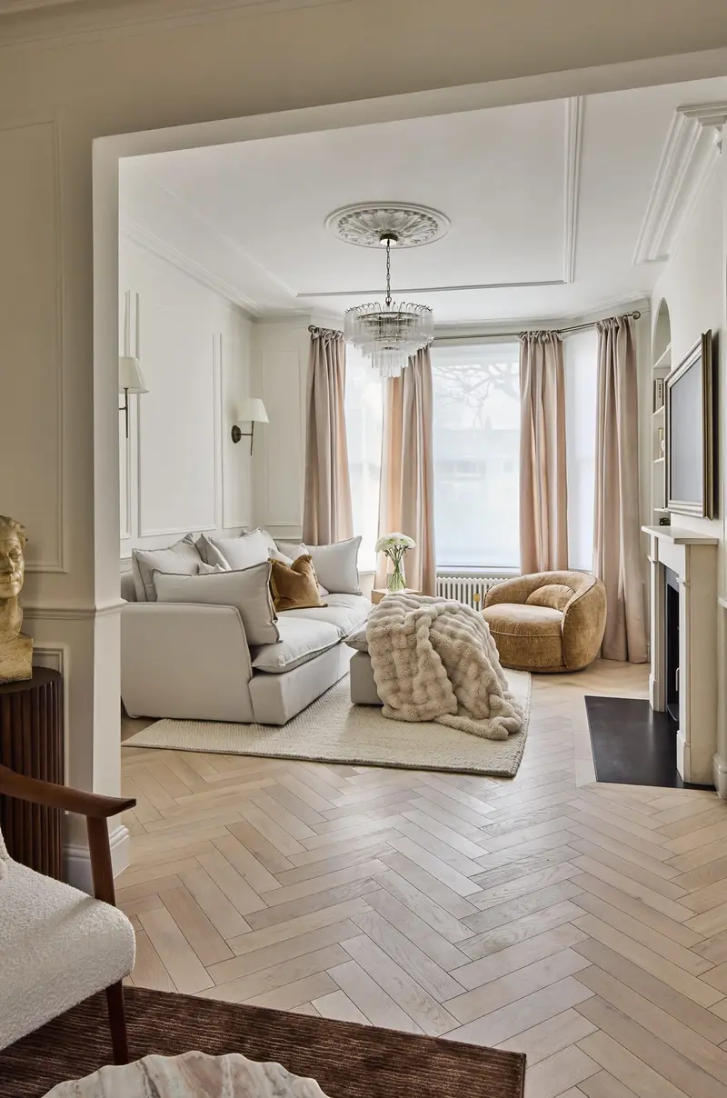 View through double doors into a cream living room with herringbone floor
