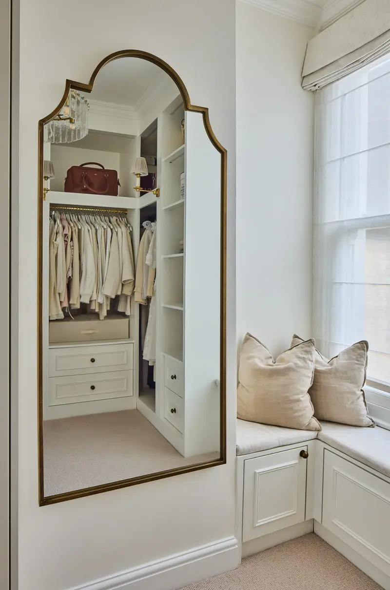 Arched full-length mirror and window seat in a dressing room