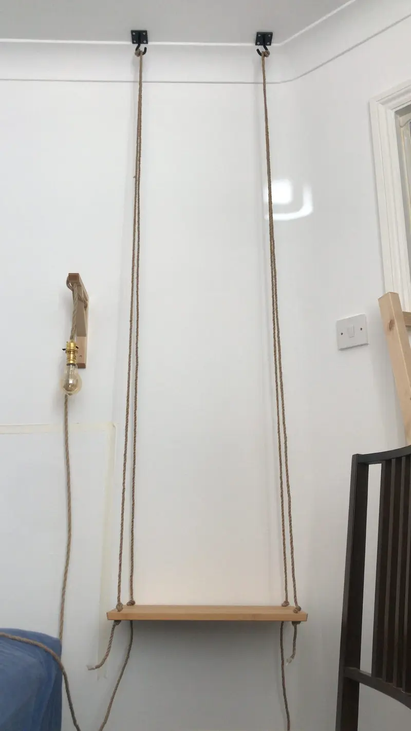 Hanging bedside table made from a chopping board and hemp rope