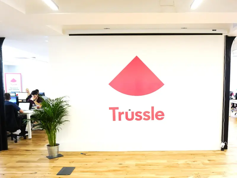 Trussle reception with a large pink logo wall and potted palm