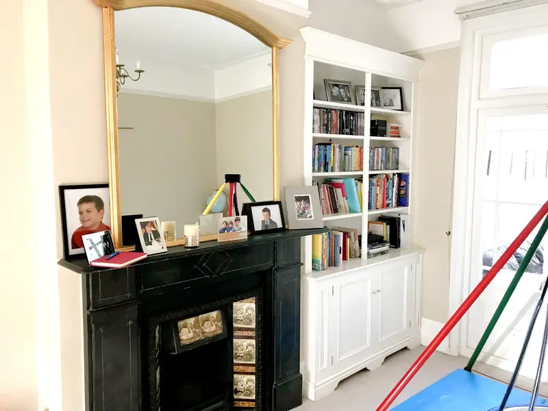 Victorian lounge with a black fireplace, gold mirror and built-in shelves